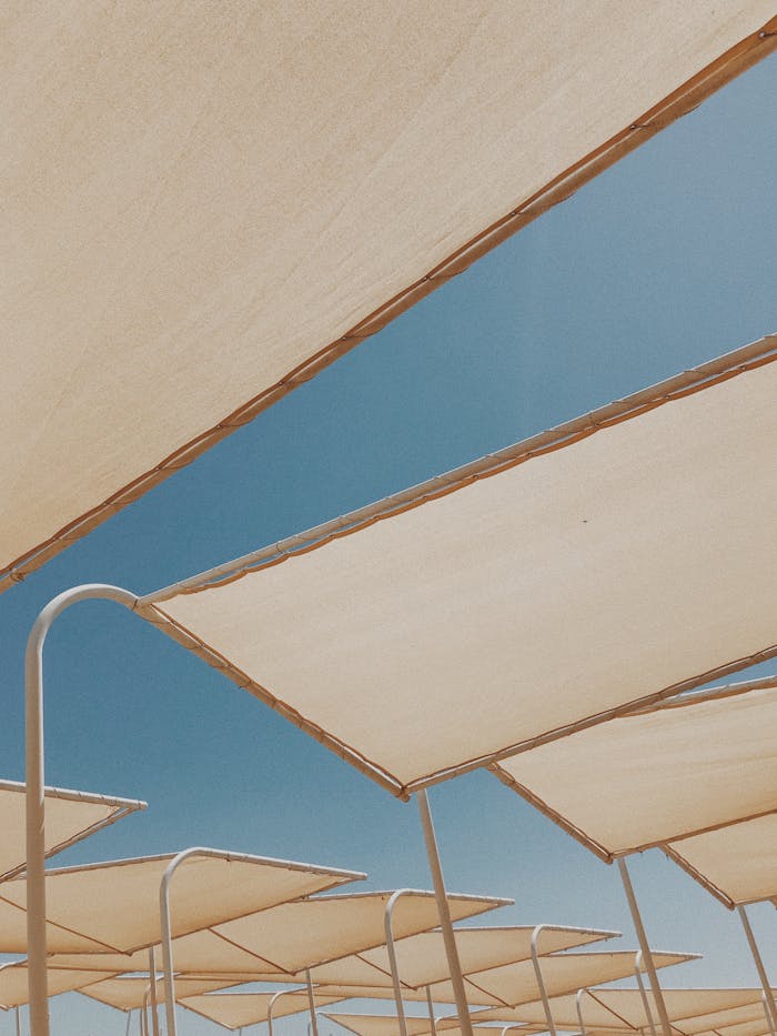 services-02 Low angle view of modern sun shades under a clear blue sky, perfect for summer concepts.