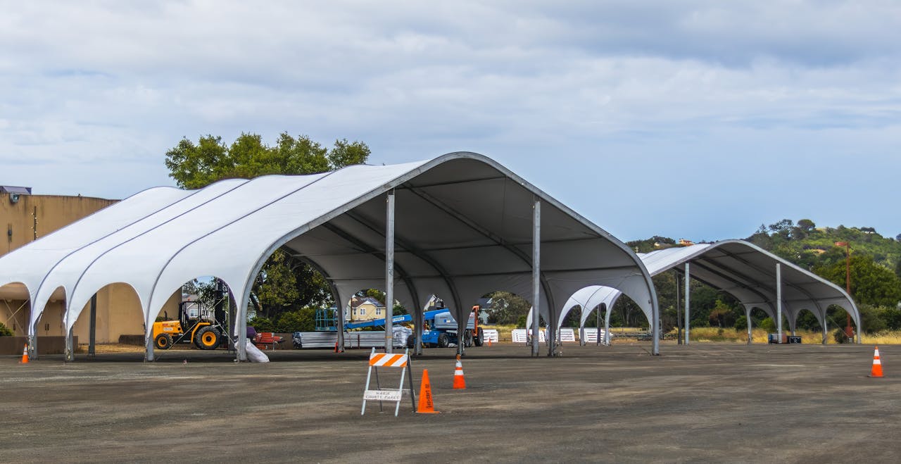 gallery-4 Large outdoor canopies set up for rural events or storage in a countryside field.