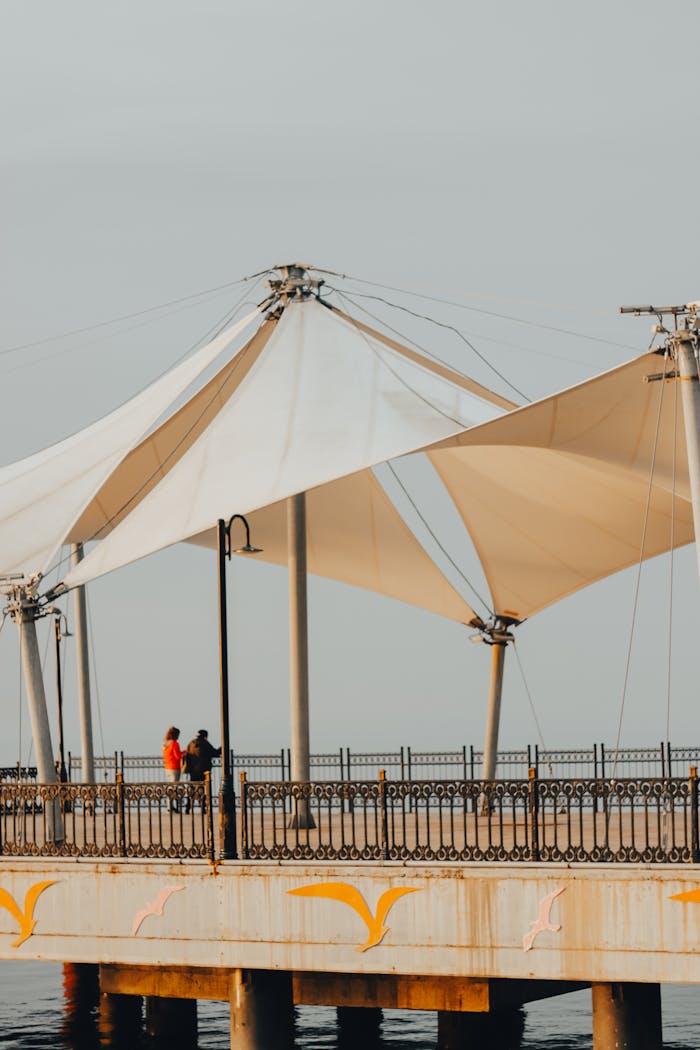 gallery-3 A modern pier with a unique geometric canopy structure against the soft colors of sunset.