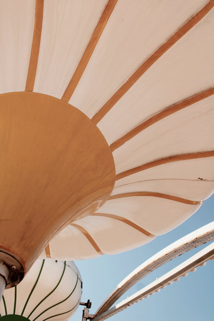 hero-img-02 Close-up of artistic sunshade structures with a blue sky backdrop, highlighting modern architecture.