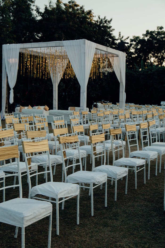 gallery-5 Charming outdoor wedding venue with white chairs and altar under evening sky.